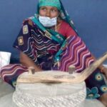 A woman uses jata, a traditional grinding stone, to make sattu. (Photo by Mohd Imran Khan)