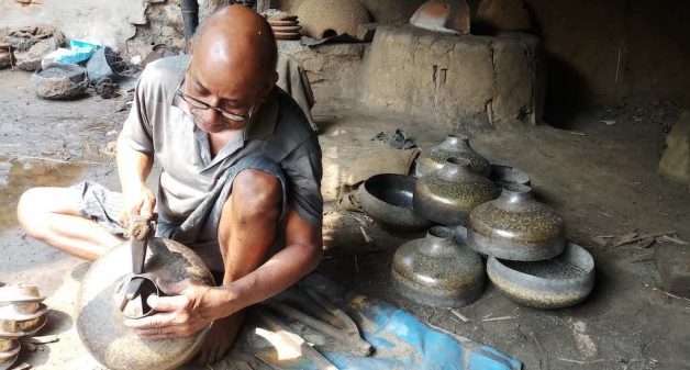 A brass smith beats into shape a traditional brass pot that is no longer in demand (Photo by Gurvinder Singh)